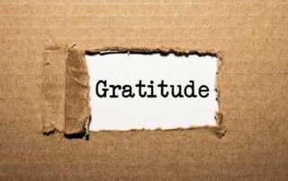 A cardboard ripped revealing the word "gratitude"