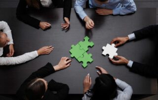 hands of a team completing a puzzle