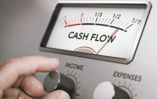 A machine that measures cashflow and a hand turning up the income button.
