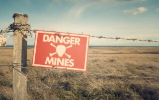 A fence with a sing that says "Danger Mines".